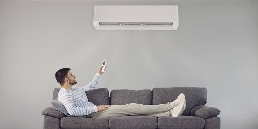 Guy sitting in living room turning on ductless ac 
